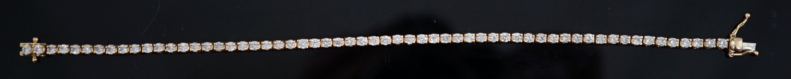 A modern 18ct gold and fifty nine stone round brilliant cut diamond set line bracelet